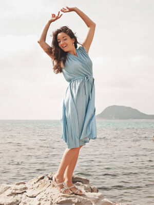 Young happy woman in blue dress posing near sea, summer vacation