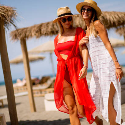 Two pretty young women walking on a beach at summer